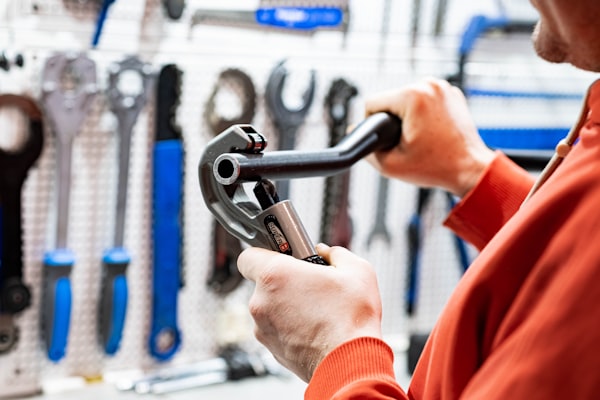 Professional plumber holding a wrench in front of a wall of tools
